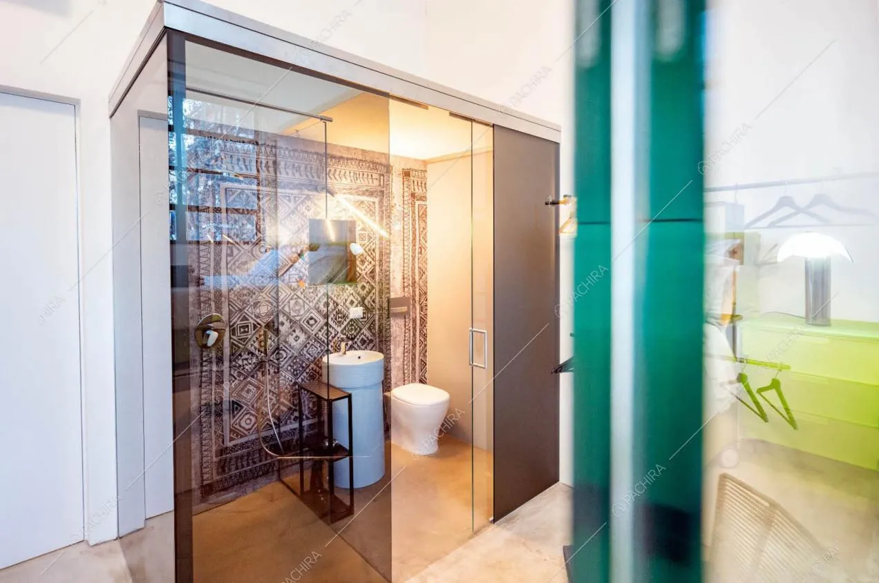 Bagno, box doccia e pavimento in resina nella camera con pareti bianche