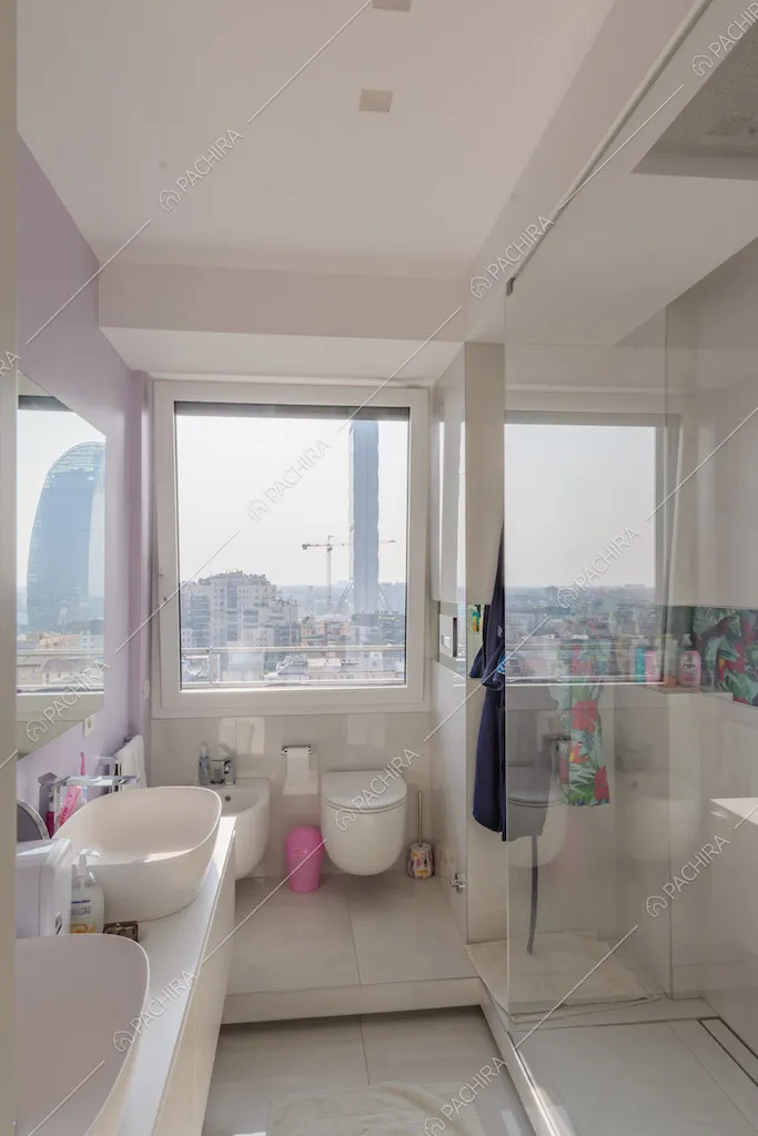 Luminoso bagno con doppio lavandino, box doccia e vetrata con vista sullo skyline 