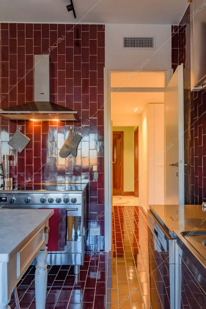 Pavimento e pareti in piastrelle rosse nella cucina a parete con tavolo da pranzo