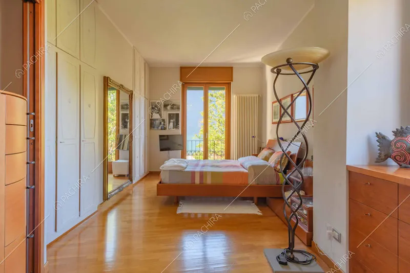 Camera da letto matrimoniale con armadi bianchi a tutta parete e porta-finestra