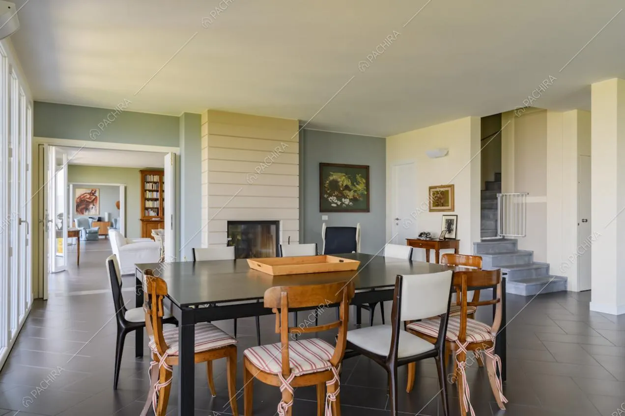 Sala da pranzo con camino, vista sui due salotti e accesso alle scale