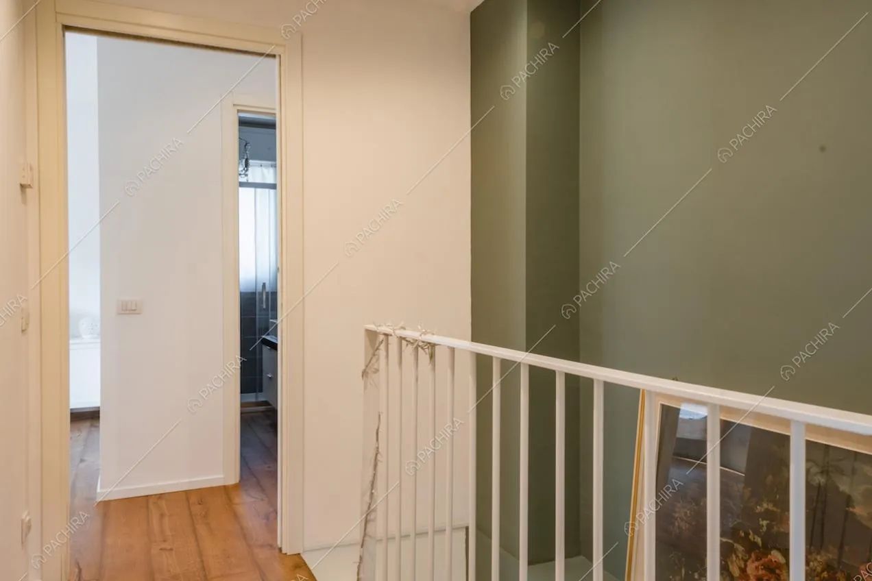 Ringhiera bianca, parete verde e pavimento in legno