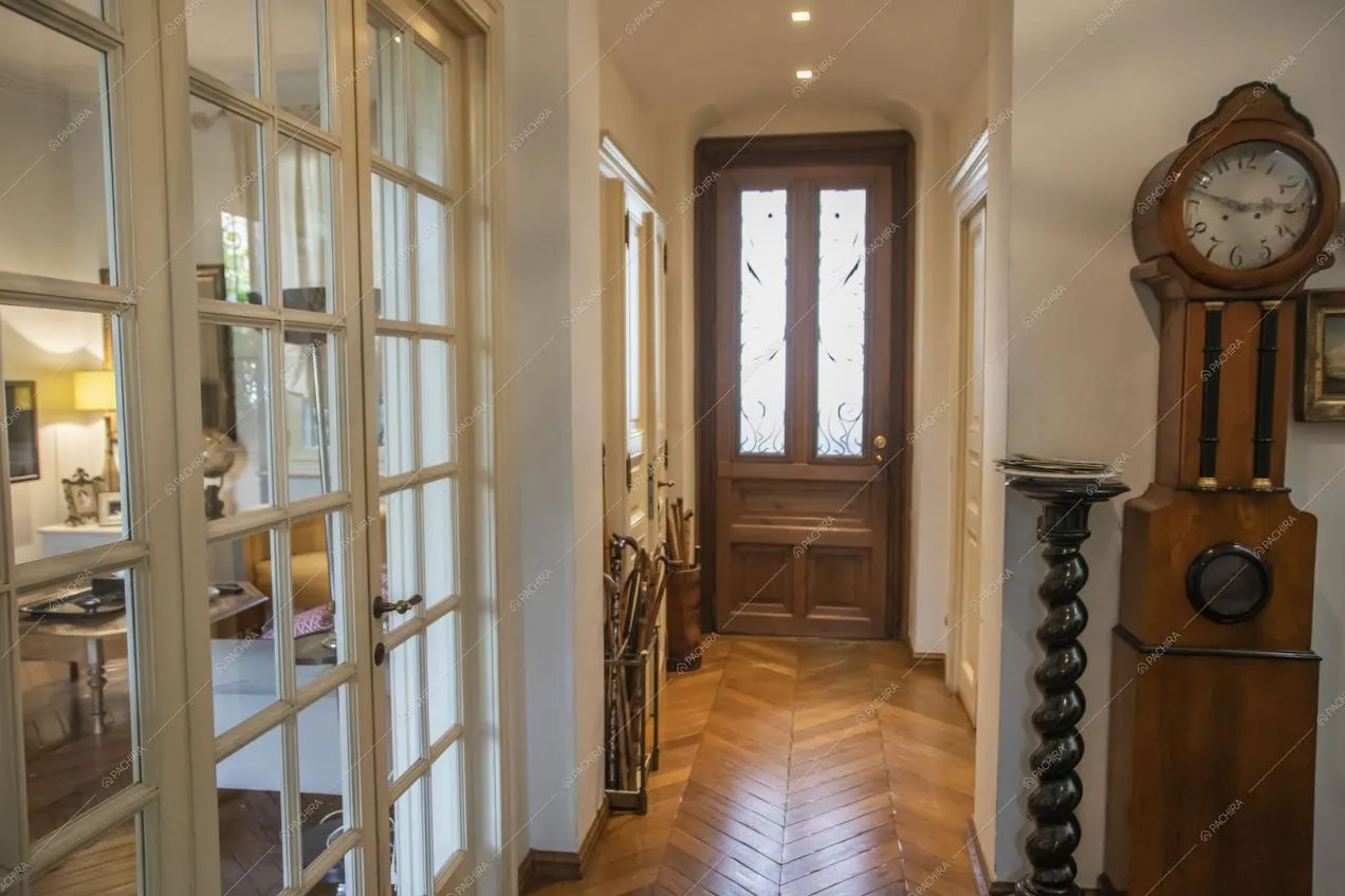 Corridoio con pavimento in parquet a spina di pesce, pareti bianche e porta a vetri