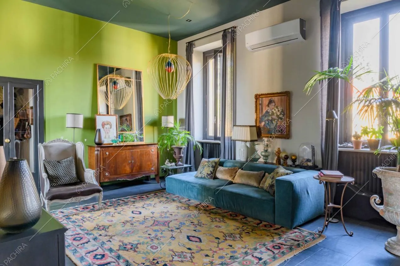 Luminosa sala da pranzo con parete verde acido, divano in velluto azzurro e pavimento nero