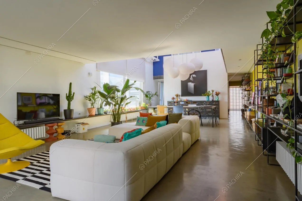Luminosa zona living con divano bianco angolare e parete gialla con libreria