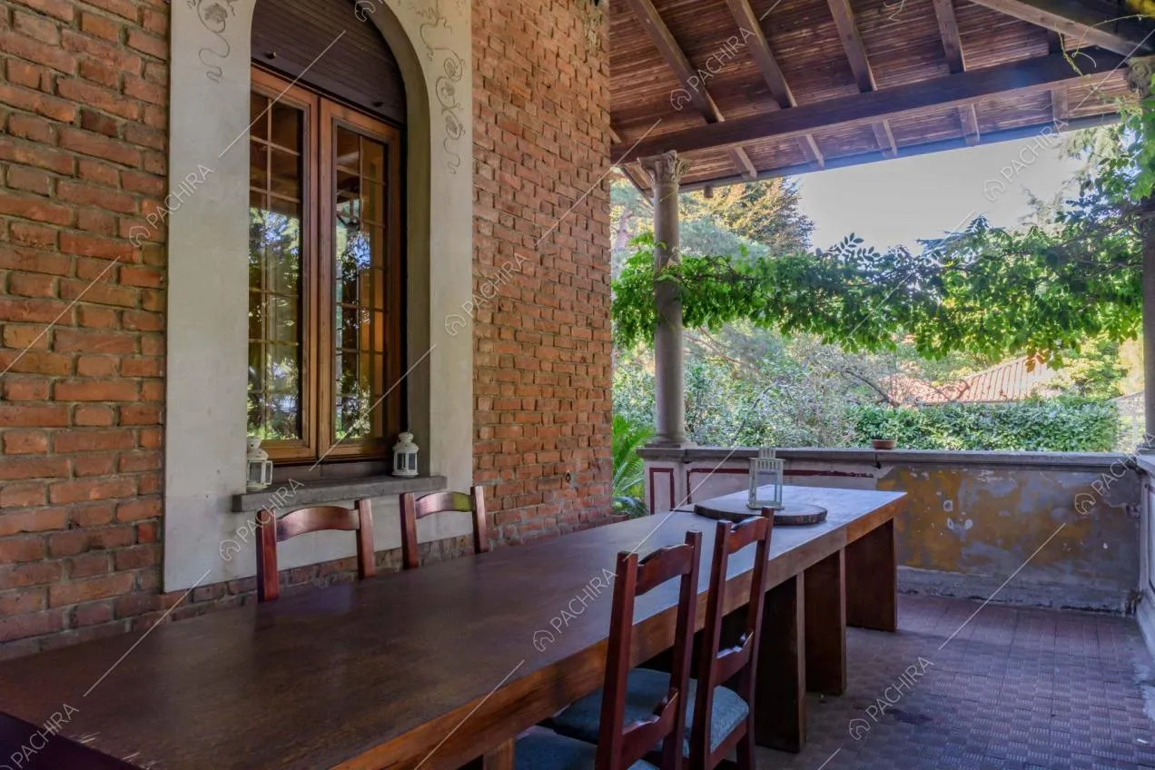 Veranda con colonne bianche, soffitto in travi in legno a vista e tavolo da pranzo