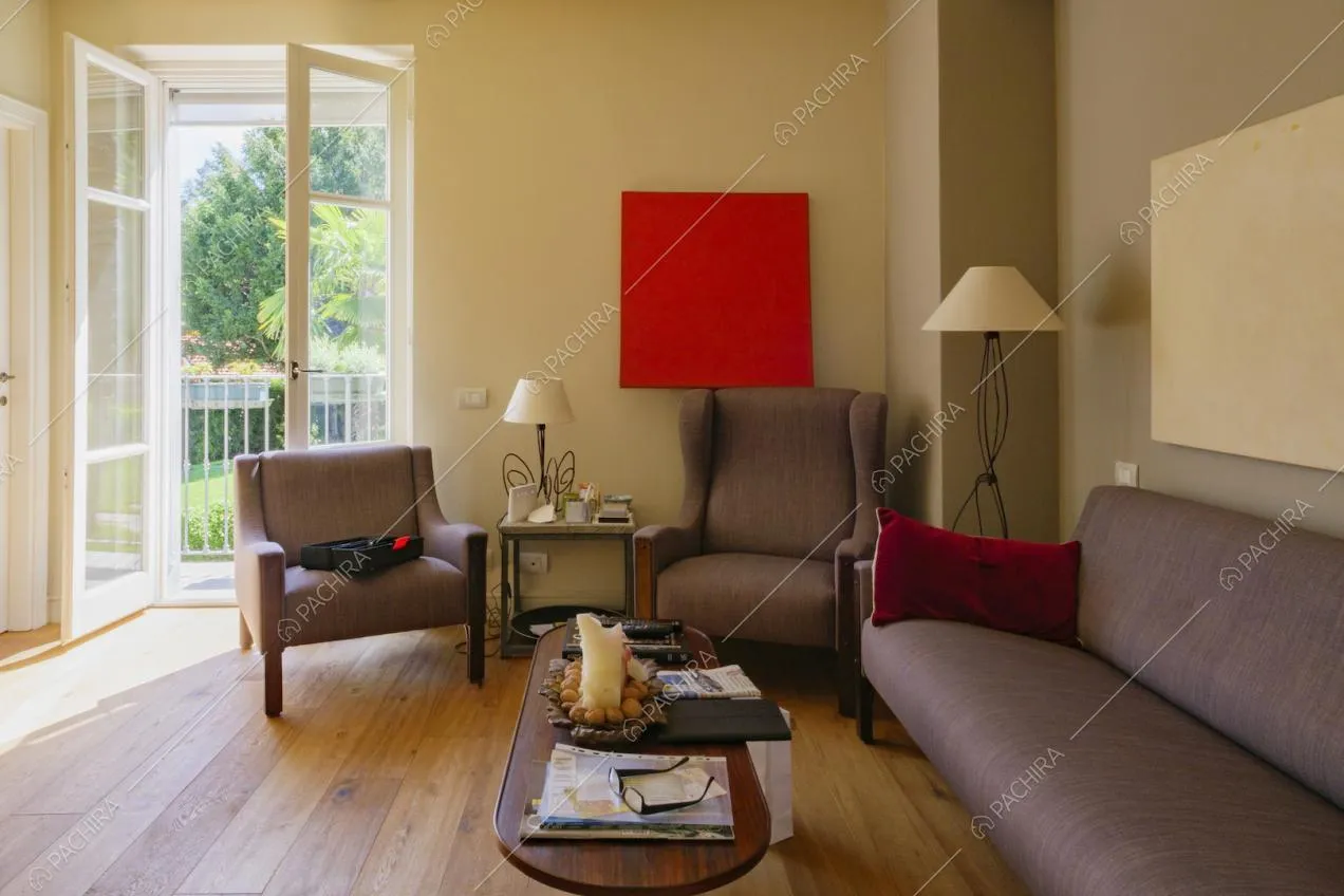 Divano e poltrone nel salotto con pavimento in parquet e porta-finestra