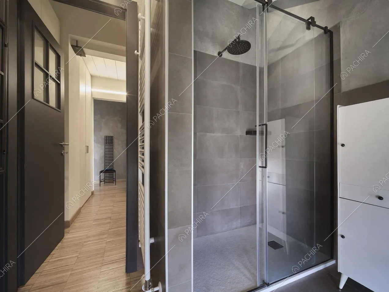 Bagno con box doccia dalle pareti grigie e vista sul corridoio con pavimento in parquet