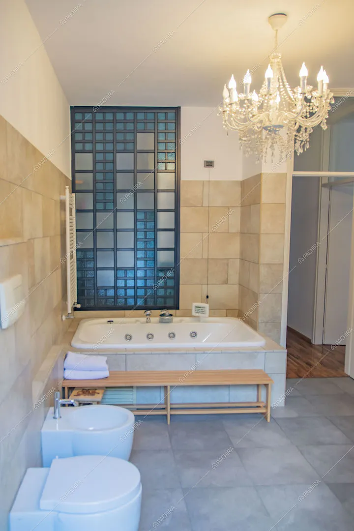 Grande bagno con vasca, parete in lastre di pietra e vista sul corridoio