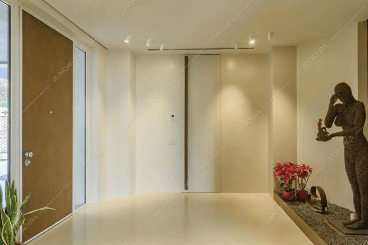 Luminoso atrio total white con vaso con ciottoli e statua