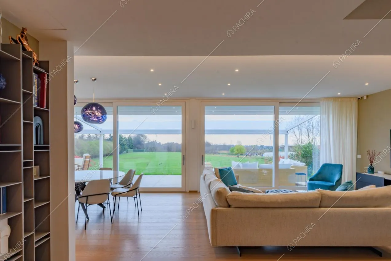 Zona living con pavimento in parquet, grandi porte-finestre scorrevoli e divano