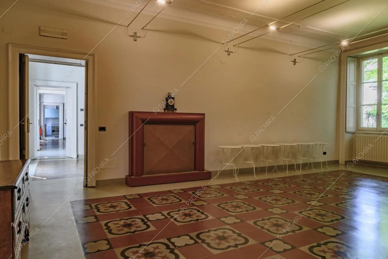 Ampia sala dalle pareti bianche con boiserie sul soffitto, pavimento in marmo e vista sulle altre stanze