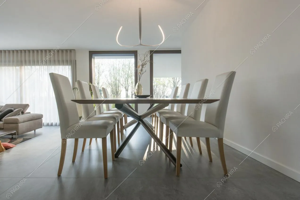 Tavolo da pranzo in luminosa sala con vetrate e pareti e soffitto bianchi