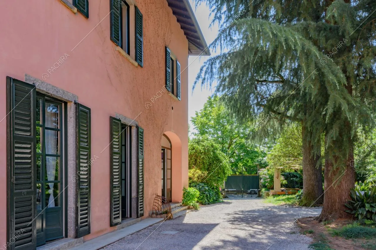 Dal giardino vista sugli esterni rosa della location con persiane verdi