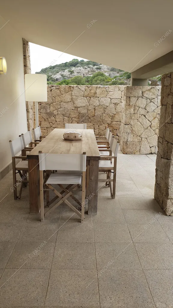 Zona pranzo esterna con tavolo in legno, sedie in tela pieghevoli e muri di pietra