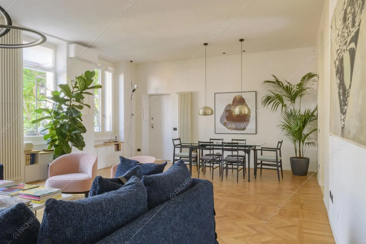 Pareti bianche con quadri, parquet e tavolo da pranzo