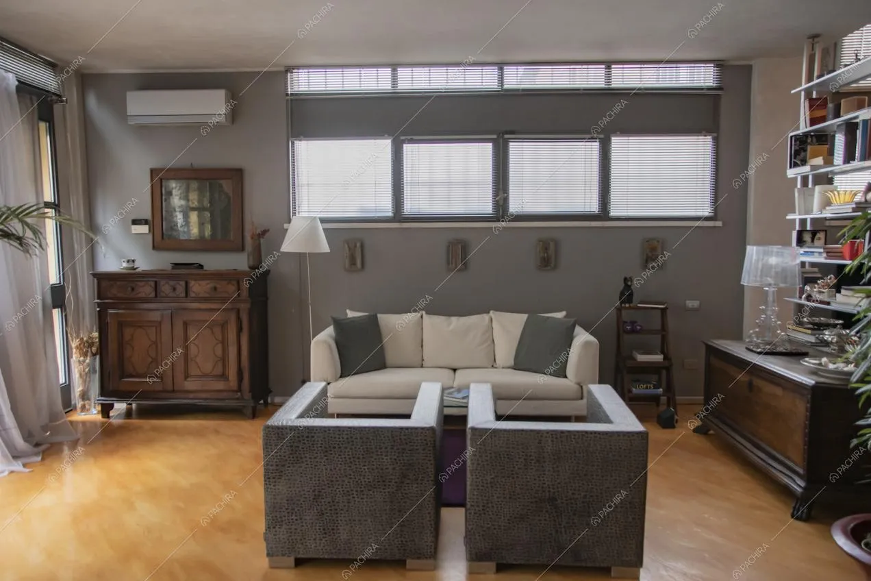 Salotto con divano bianco, poltrone, pareti grigie e pavimento in parquet