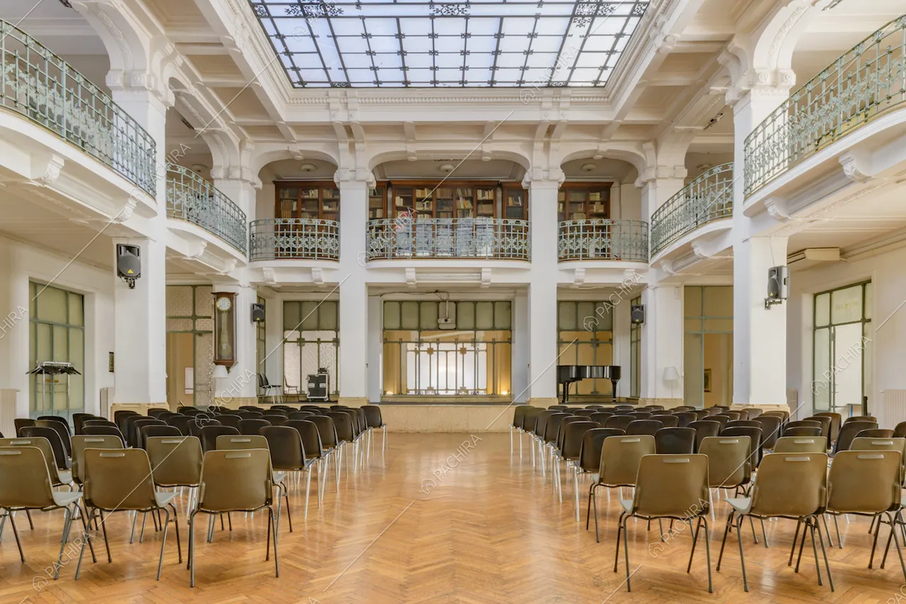 Ampio salone illuminato da lucernario, con pavimento in parquet a spina di pesce e colonne bianche con boiserie