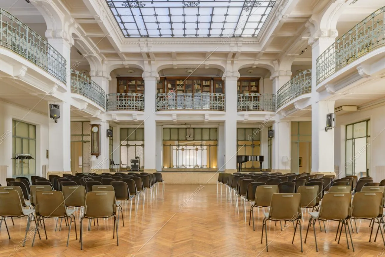 Ampio salone illuminato da lucernario, con pavimento in parquet a spina di pesce e colonne bianche con boiserie