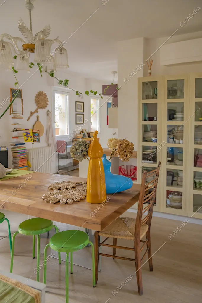 Sala da pranzo con tavolo in legno e sgabelli verde pisello
