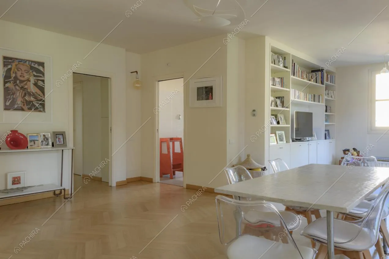 Tavolo da pranzo rettangolare, libreria con televisore e quadro moderno appeso alla parete