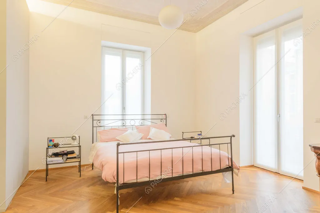 Ampia camera da letto matrimoniale con pavimento in parquet a spina di pesce