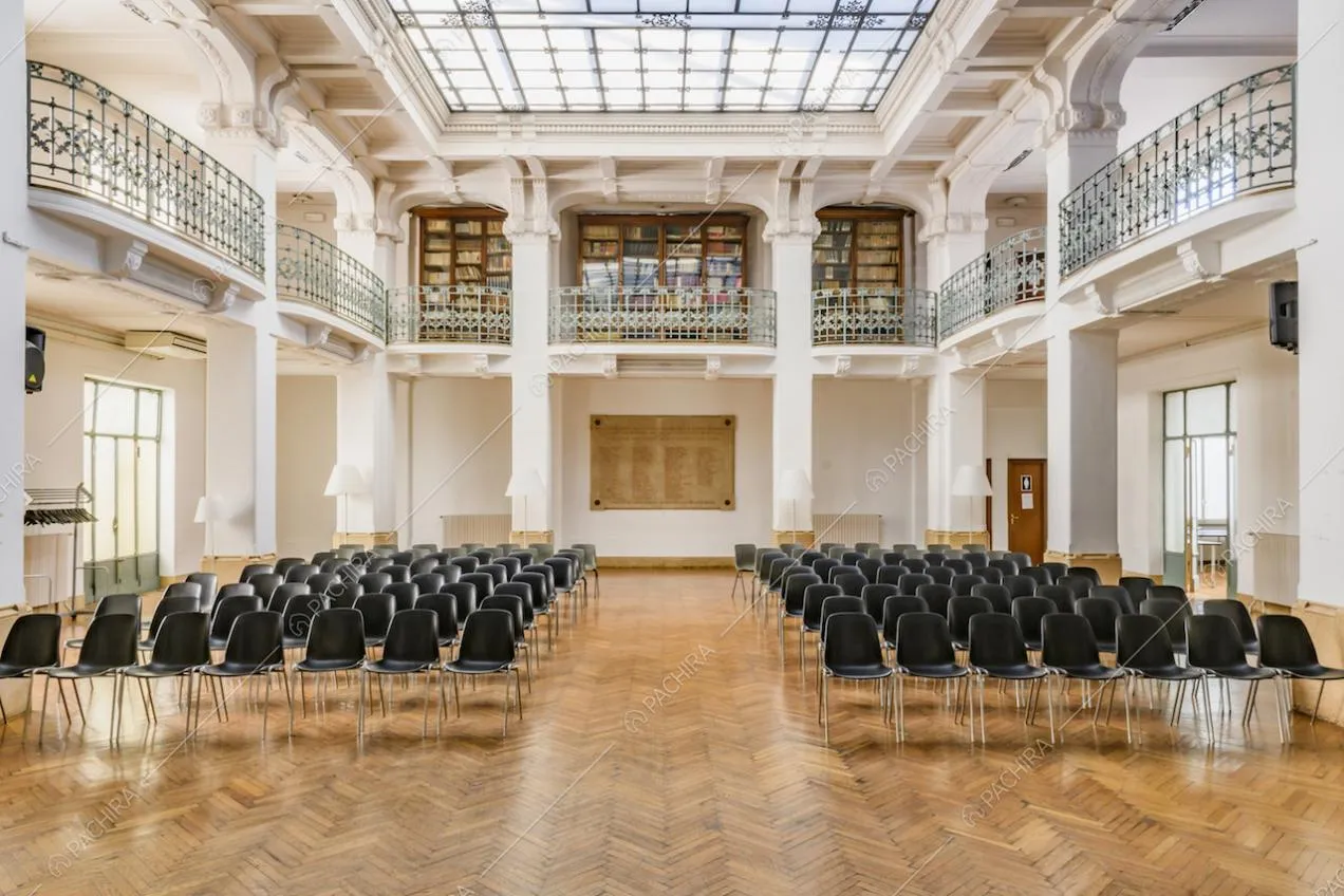 Salone con pavimento in parquet a spina di pesce, pareti e colonne bianche, illuminato dal lucernario