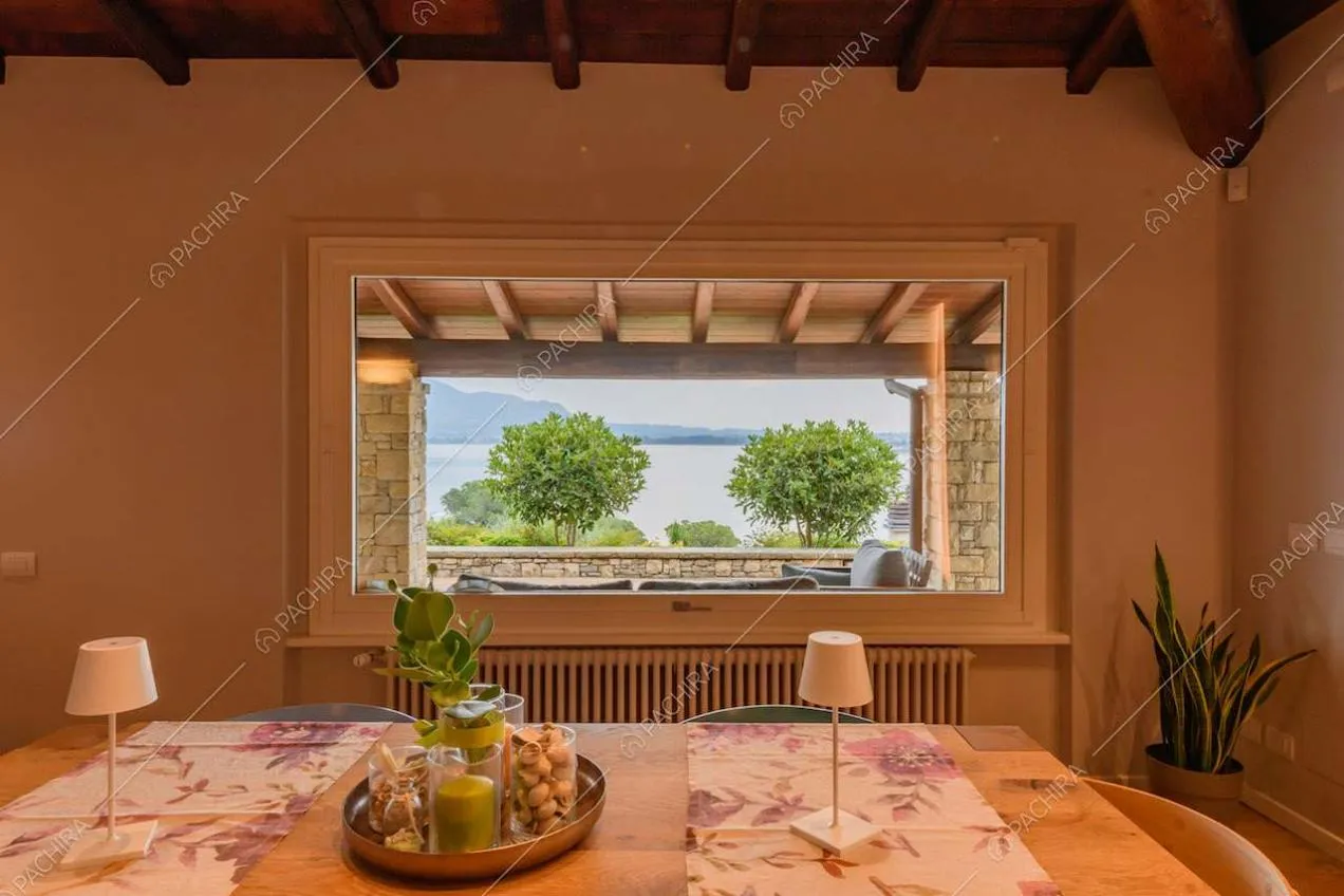 Tavolo da pranzo in legno nell'open space con travi in legno sul soffitto e vista sul lago