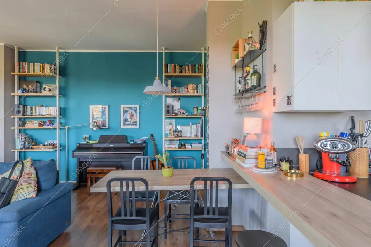 Tavolo da pranzo in legno, sedie nere e parete azzurra nella zona living