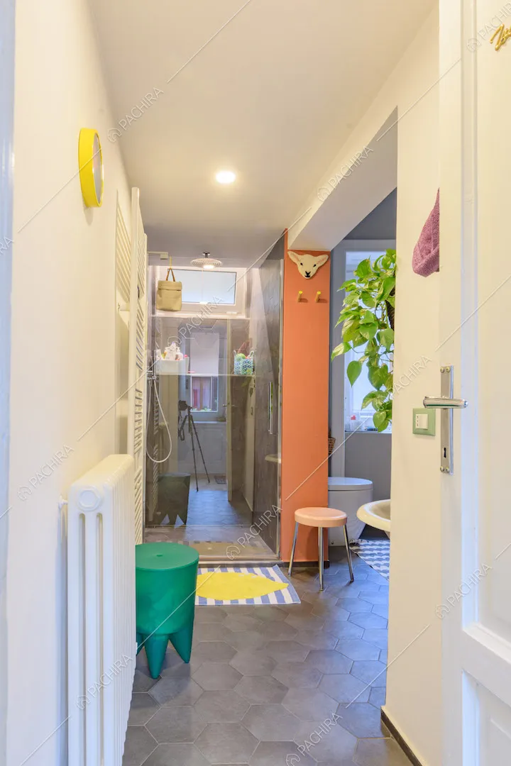 Bagno con pavimento in cementine grigie, box doccia e pareti bianche