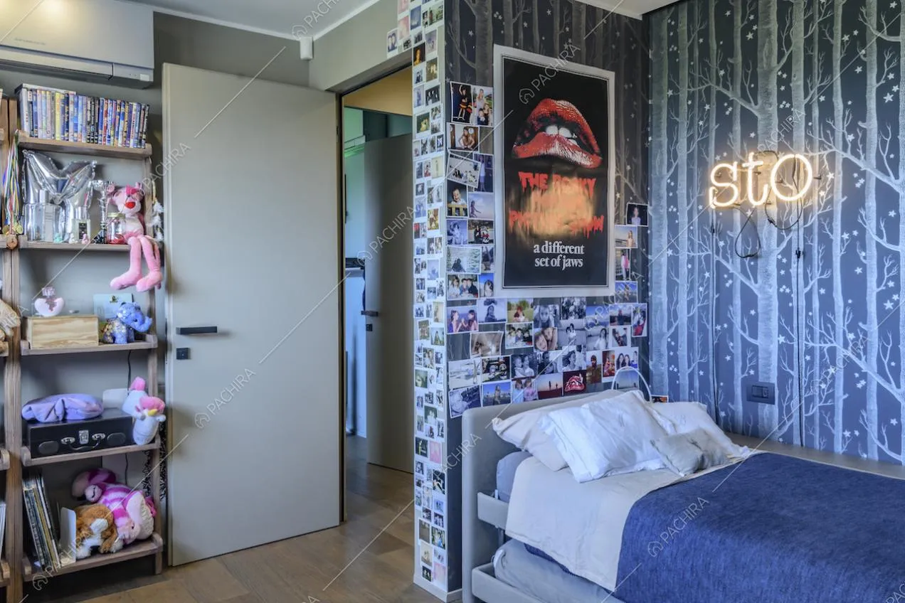 Fotografie appese alla parete, carta da parati nei toni del blu e letto singolo