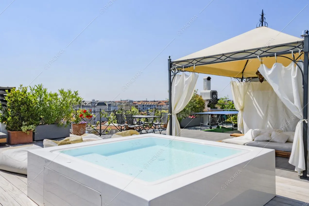 Piscina quadrata e gazebo in ferro con tende bianche ai lati