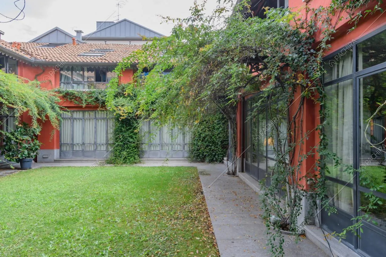 Giardino con rampicanti e vista sugli esterni rossi e sulle vetrate