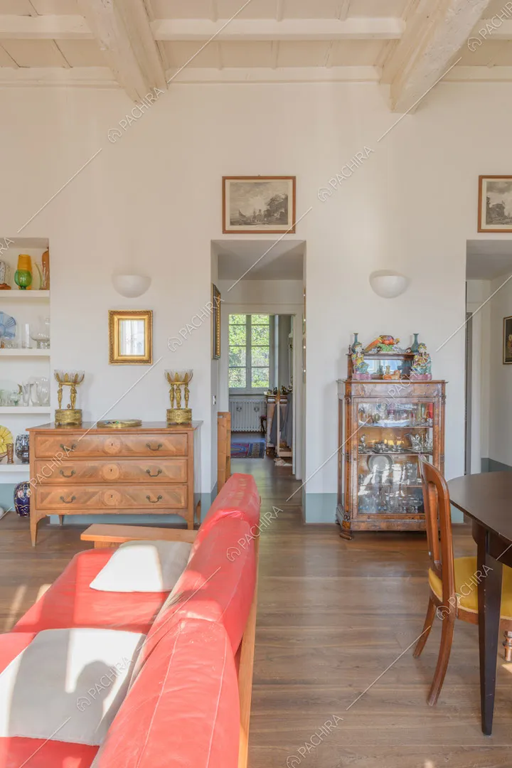 Divano rosso nella zona living con pareti bianche, soffitto a cassettoni e pavimento in parquet