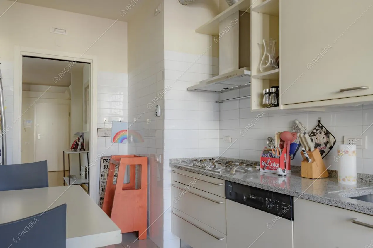 Cucina con mobili chiari e pareti rivestite con piastrelle bianche