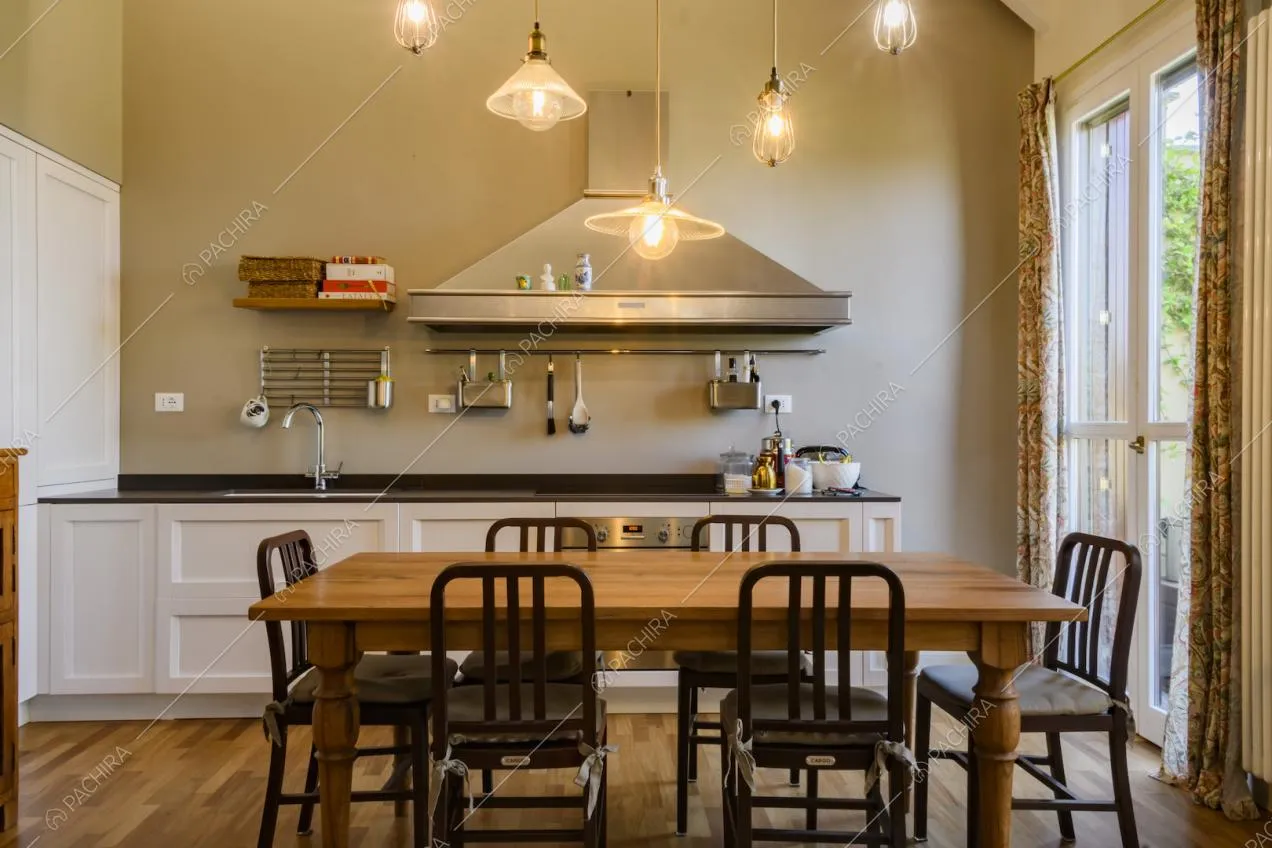 Tavolo da pranzo in legno con sedie davanti alla cucina a vista 