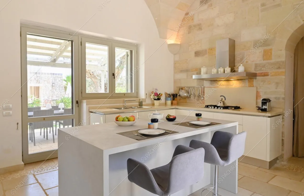 Bancone con sgabelli sull'isola della cucina dalla quale, tramite porta-finestra, si accede alla veranda 