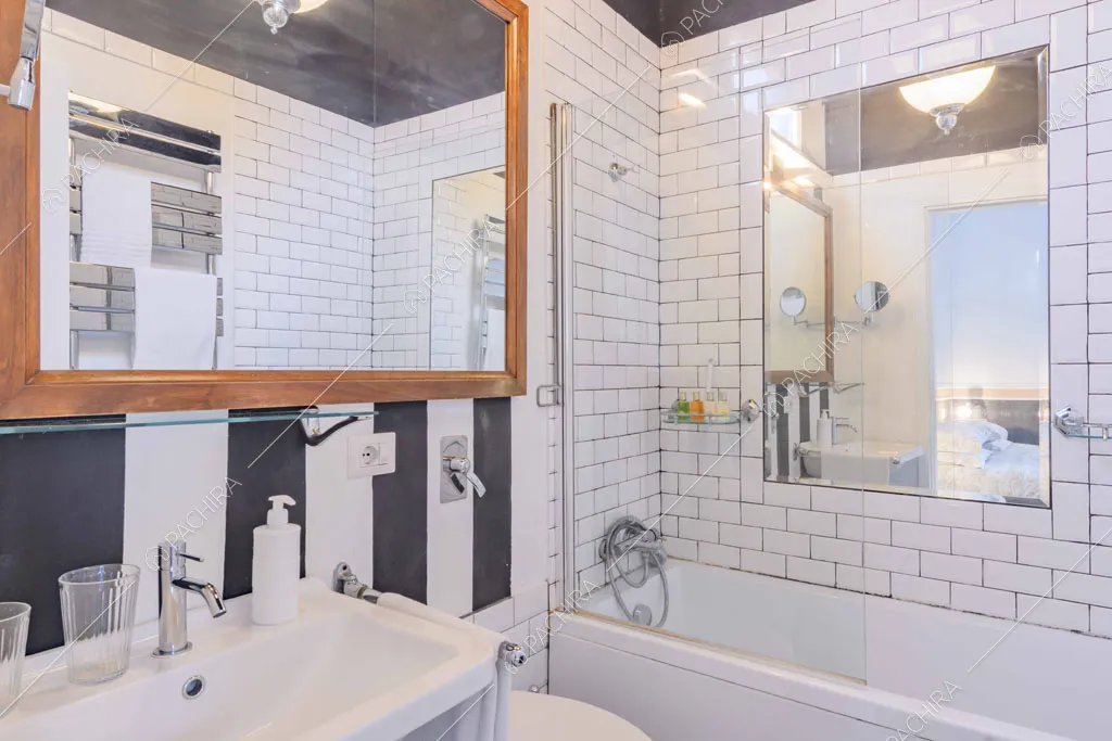 Bagno con carta da parati a strisce bianche e nere e pareti in mattonelle bianche