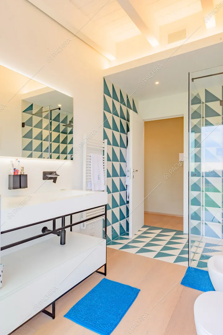Bagno con pavimento in parquet e box doccia con piastrelle a triangoli blu e bianche