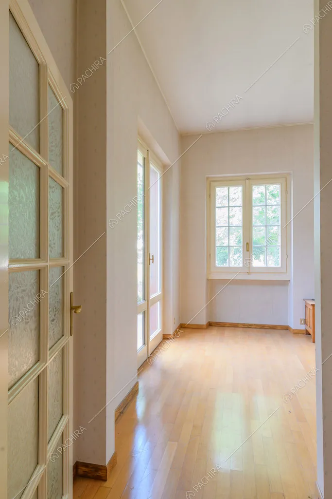 Ampia stanza con pavimento in parquet e pareti bianche