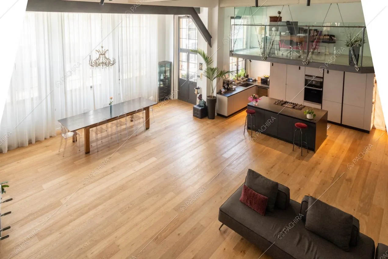Dal soppalco vista sul soggiorno arredato in stile minimal con divano angolare e cucina a vista con isola