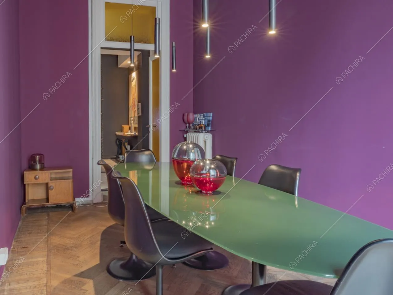 Lungo tavolo con intorno sedie di design nere e pareti color viola