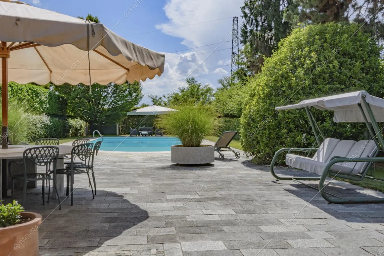 Vista sulla piscina dal giardino con pavimento in pietra
