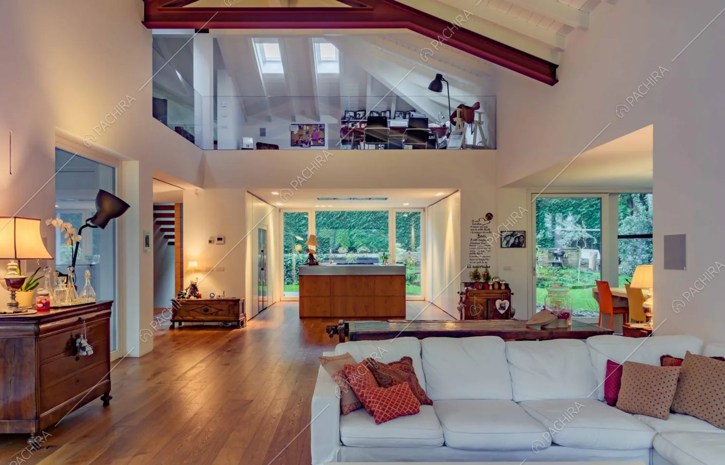 Divano bianco angolare del salotto con pavimento in parquet e vista sullo studio e sulla cucina con isola