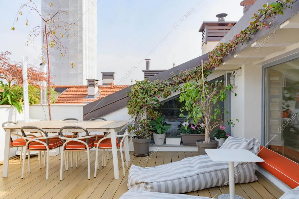 Pouf grigi e bianchi sulla terrazza con tavolo da pranzo e vista sullo skyline