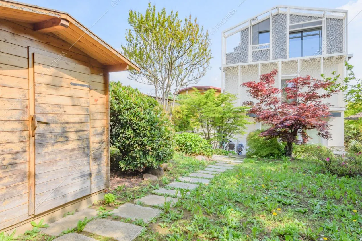Giardino con vialetto in lastre di pietra e capanno in legno