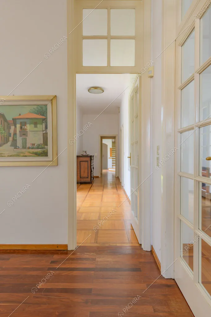 Vista sul luminoso corridoio con pareti bianche e pavimento in parquet