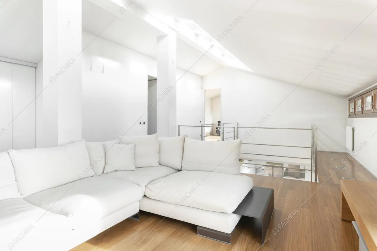 Divano ad angolo bianco con cuscini e parquet