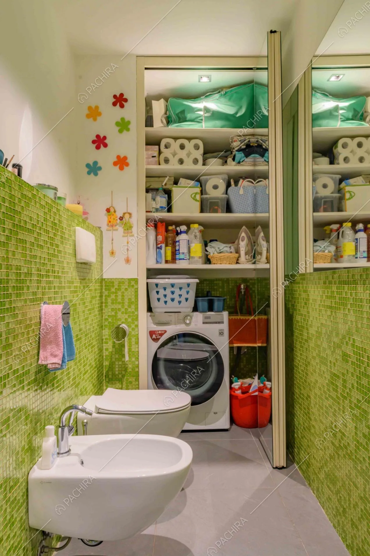 Bagno con sanitari sospesi e pareti in piastrelline verdi