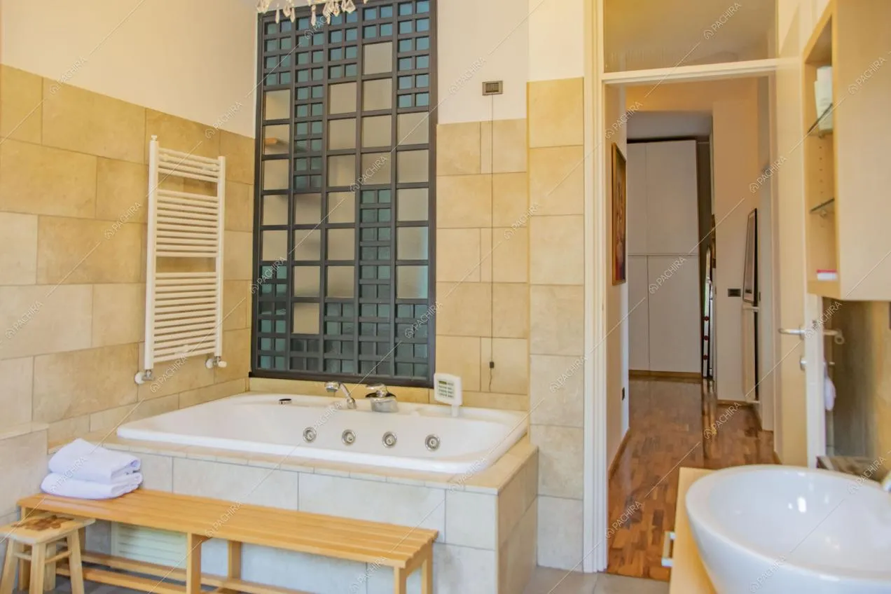 Luminoso bagno con grande vasca e vista sul corridoio con pavimento in parquet